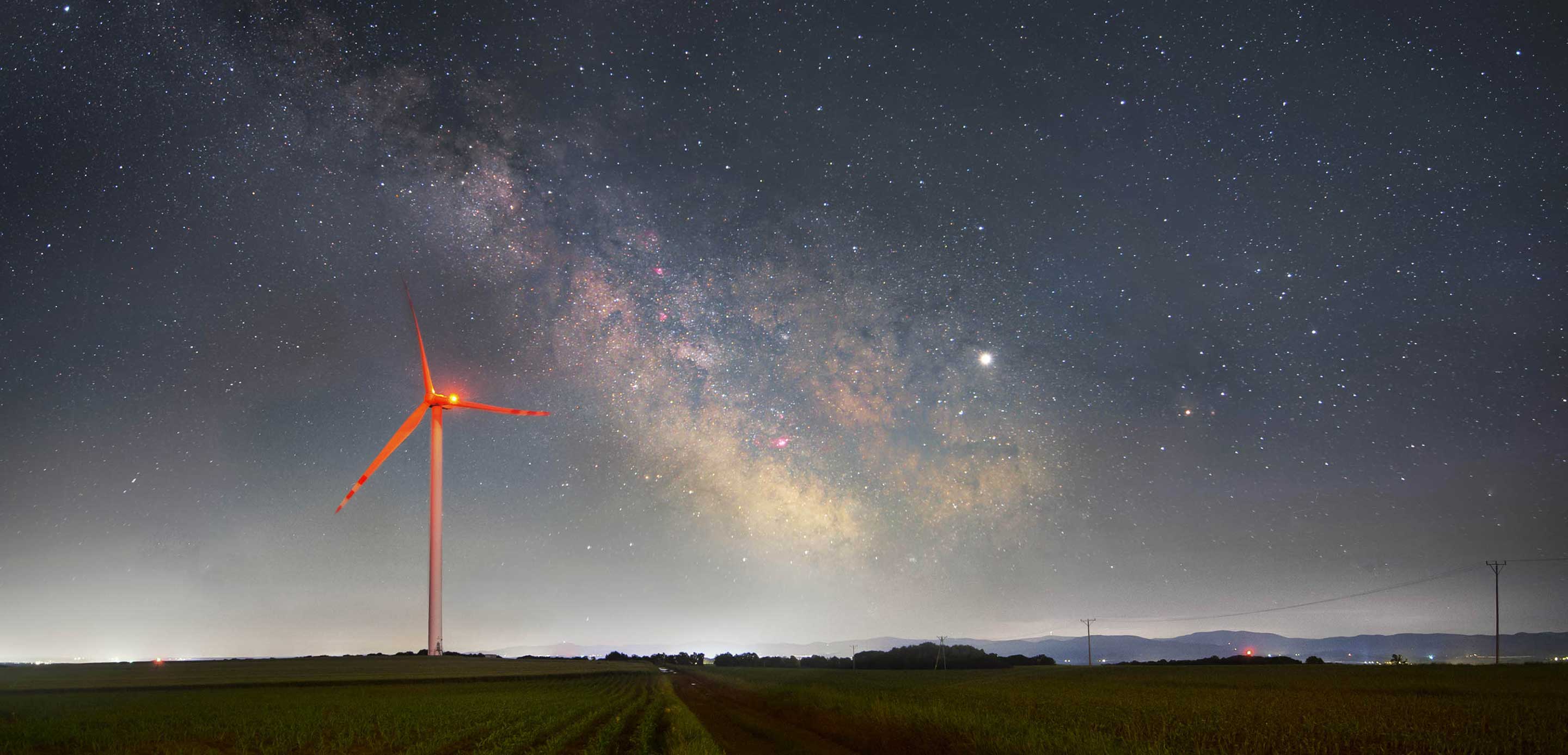 A wind turbine illuminated against the night sky, harnessing renewable energy in the darkness. A wind turbine illuminated against the night sky, harnessing renewable energy in the darkness.